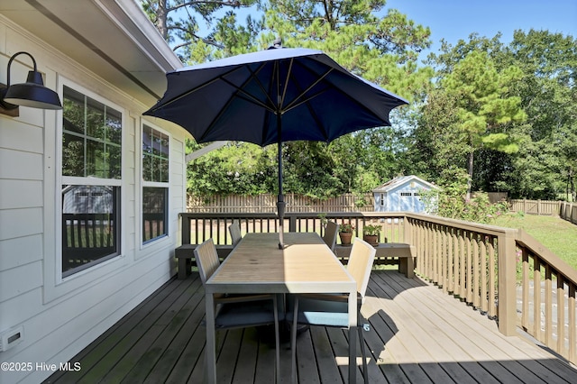deck featuring an outdoor structure, outdoor dining area, and a fenced backyard
