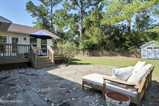 view of patio / terrace with a storage unit, a deck, fence private yard, and an outdoor structure