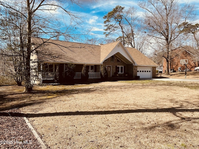 view of front of home with dirt driveway, a shingled roof, covered porch, and an attached garage