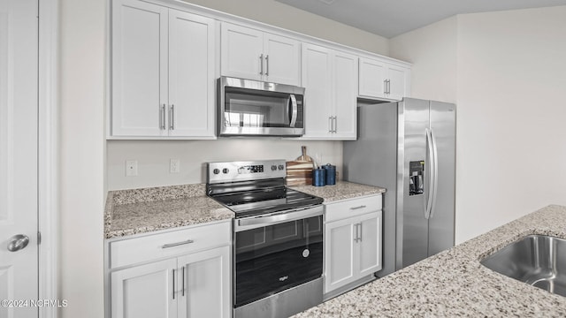 kitchen with white cabinetry, appliances with stainless steel finishes, light stone countertops, and sink