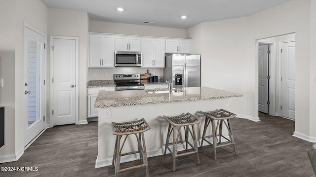 kitchen featuring stainless steel appliances, a kitchen island with sink, sink, and white cabinets