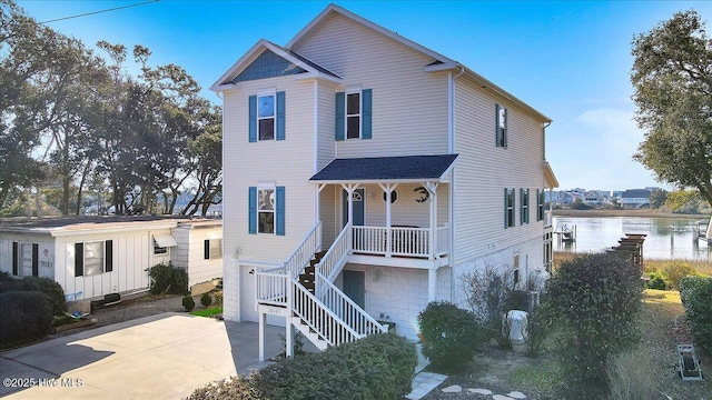 view of front of property with a water view, driveway, stairway, covered porch, and an attached garage