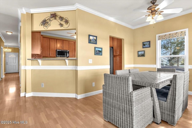 kitchen featuring stainless steel microwave, ceiling fan, light wood-type flooring, ornamental molding, and brown cabinetry