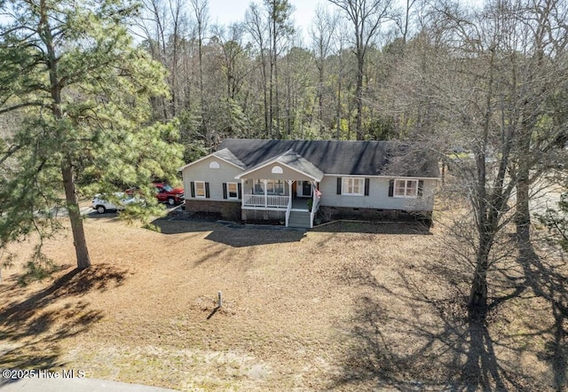 ranch-style home featuring a forest view, crawl space, covered porch, and dirt driveway