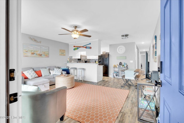 living room featuring light wood-style flooring and ceiling fan