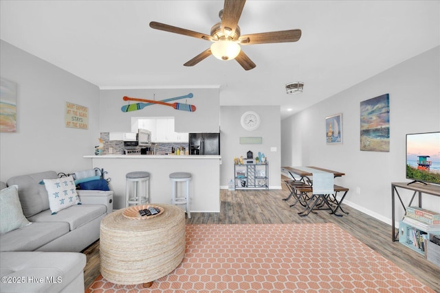 living area with a ceiling fan, baseboards, and wood finished floors