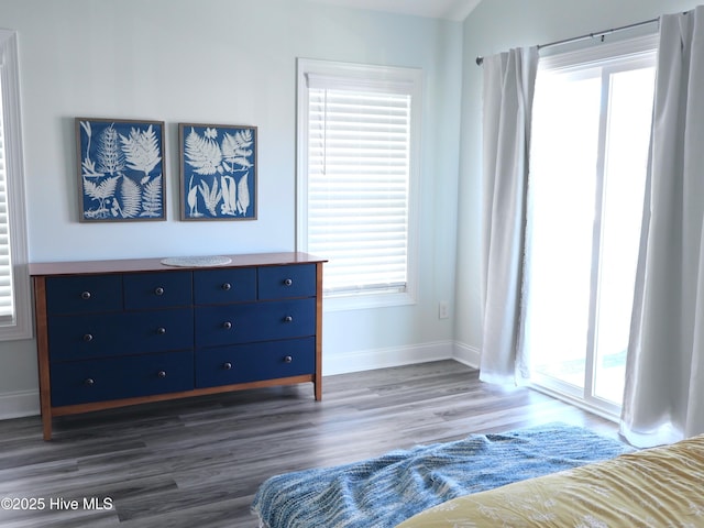 unfurnished bedroom with multiple windows, dark wood finished floors, and baseboards