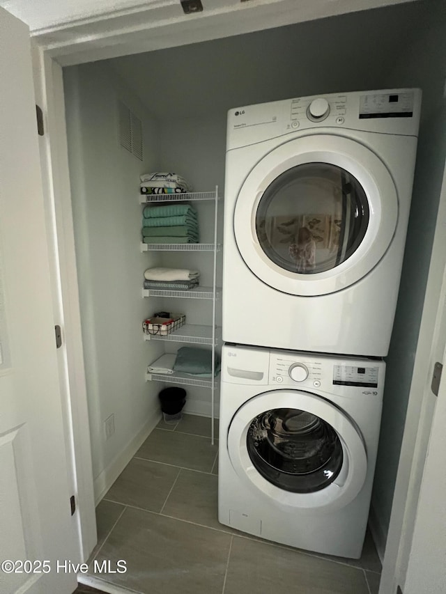 laundry room with laundry area, visible vents, baseboards, stacked washer / dryer, and tile patterned floors