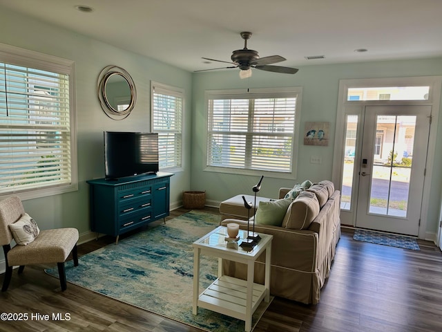 living room featuring dark wood-type flooring, visible vents, ceiling fan, and baseboards