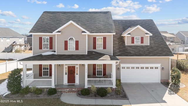 view of front of house with covered porch, concrete driveway, fence, a garage, and a residential view