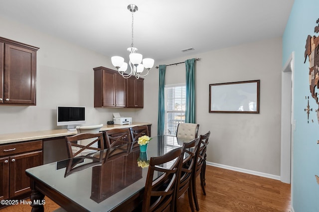 dining area featuring baseboards, visible vents, dark wood-style flooring, built in desk, and a notable chandelier