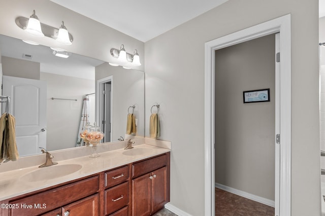 bathroom with visible vents, a sink, baseboards, and double vanity