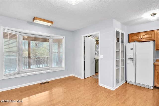 kitchen featuring light hardwood / wood-style floors, a textured ceiling, and white fridge with ice dispenser