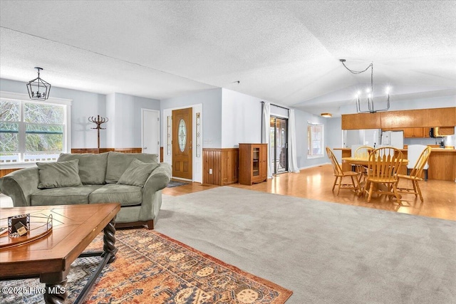 living room featuring lofted ceiling, light carpet, and a textured ceiling