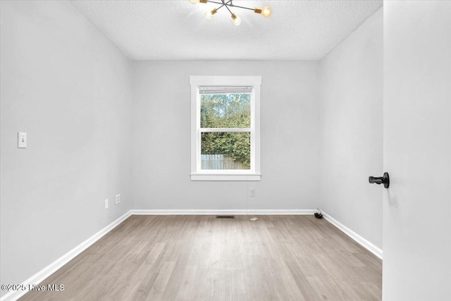 unfurnished room with a textured ceiling and light wood-type flooring