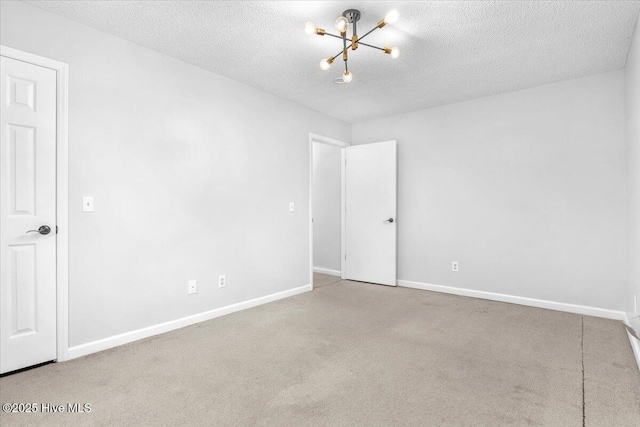 empty room featuring an inviting chandelier, light colored carpet, and a textured ceiling