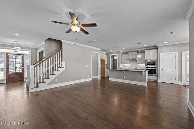 unfurnished living room featuring crown molding, sink, dark hardwood / wood-style floors, and ceiling fan