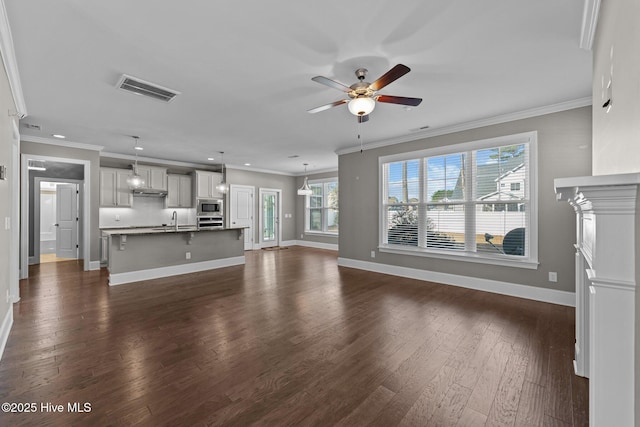 unfurnished living room with ceiling fan, sink, dark hardwood / wood-style floors, and crown molding