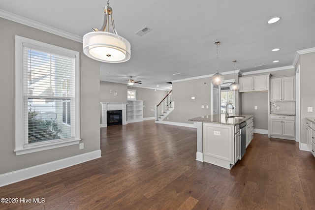 kitchen featuring an island with sink, stainless steel dishwasher, pendant lighting, dark hardwood / wood-style flooring, and white cabinetry