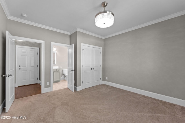 unfurnished bedroom featuring ensuite bathroom, a closet, crown molding, and light colored carpet