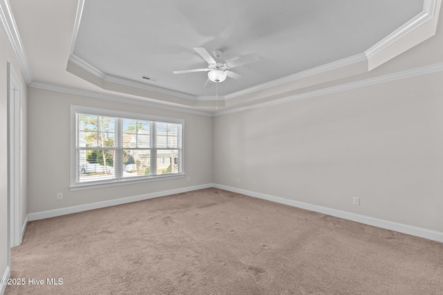 carpeted spare room with crown molding, ceiling fan, and a raised ceiling