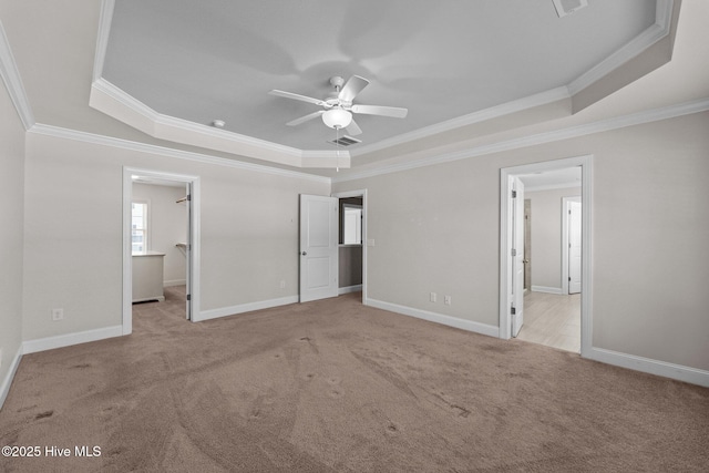 unfurnished bedroom featuring a spacious closet, ceiling fan, a raised ceiling, light carpet, and ornamental molding