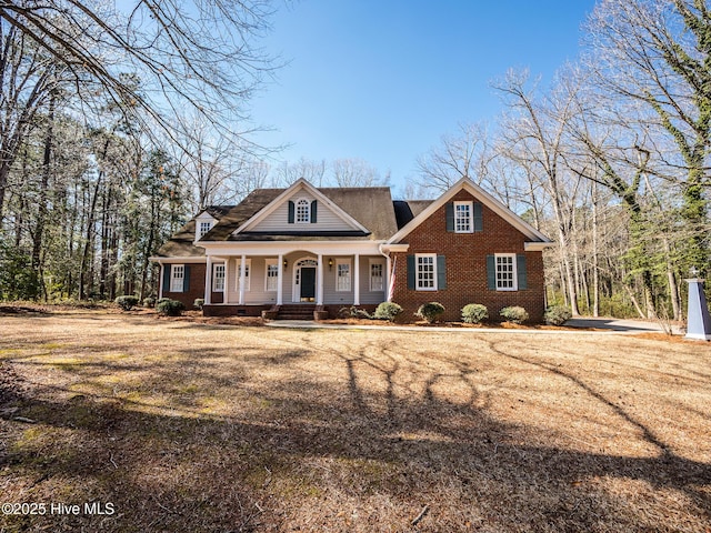 view of front of house with a front yard, covered porch, and brick siding