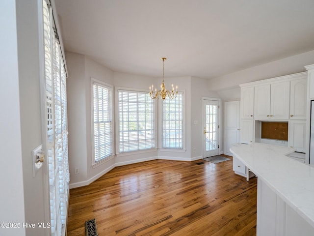 unfurnished dining area featuring a chandelier, visible vents, light wood-style flooring, and baseboards