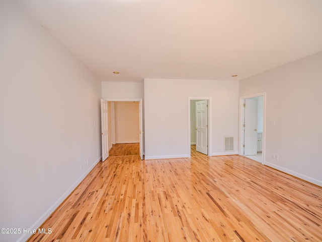 empty room featuring light wood-style flooring, visible vents, and baseboards