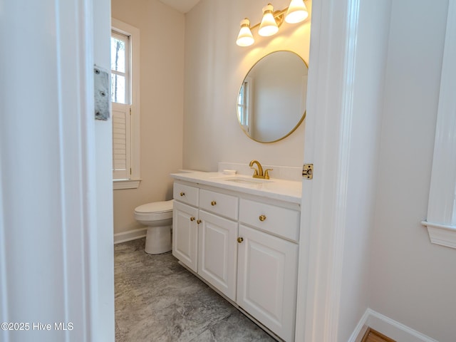 bathroom featuring vanity, toilet, and baseboards