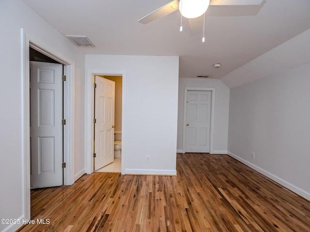 unfurnished bedroom with lofted ceiling, visible vents, baseboards, and wood finished floors