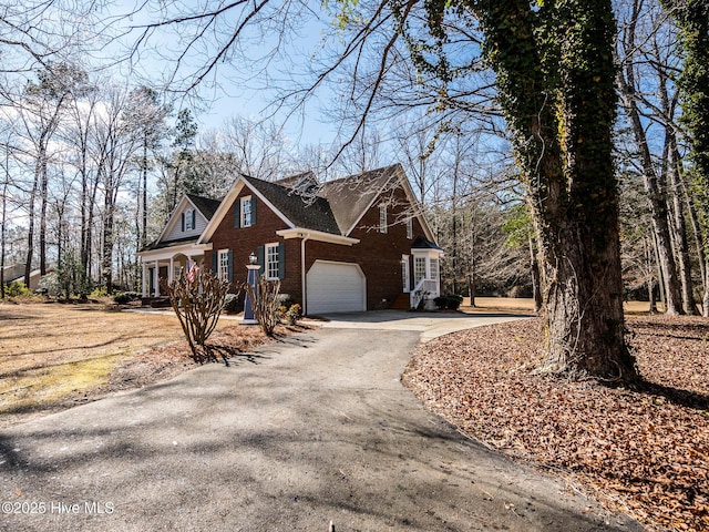 view of side of home featuring a garage, brick siding, and driveway