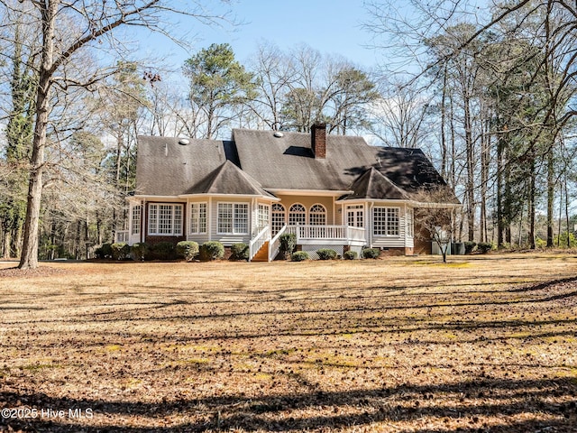 back of property with covered porch and a chimney