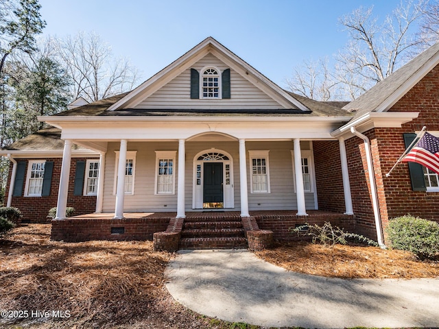 neoclassical / greek revival house with crawl space, covered porch, roof with shingles, and brick siding