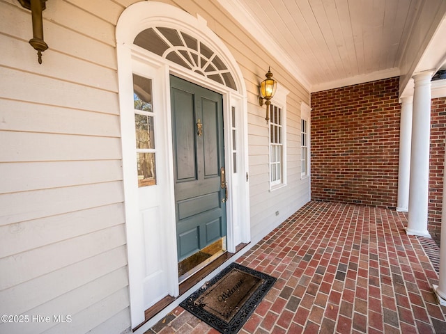 view of exterior entry with covered porch and brick siding