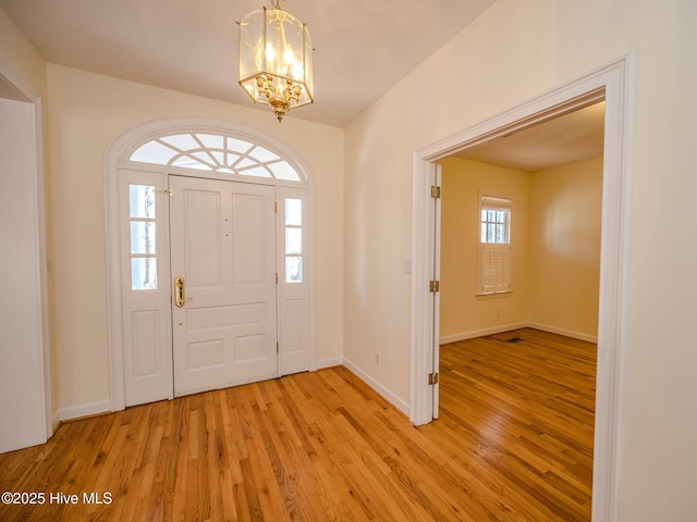 entrance foyer featuring light wood-style flooring, baseboards, and an inviting chandelier