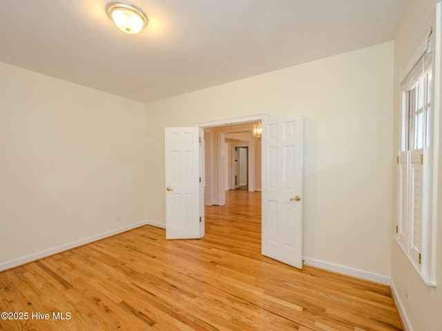 empty room featuring light wood finished floors and baseboards