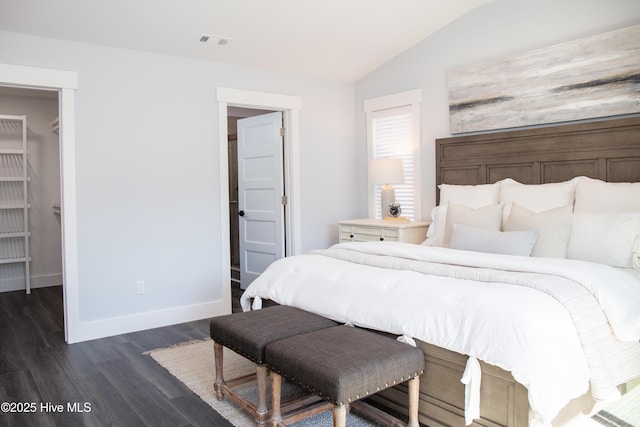 bedroom featuring vaulted ceiling, dark hardwood / wood-style floors, and a spacious closet