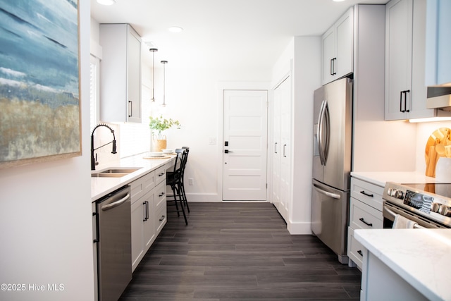 kitchen with appliances with stainless steel finishes, decorative light fixtures, sink, and white cabinets