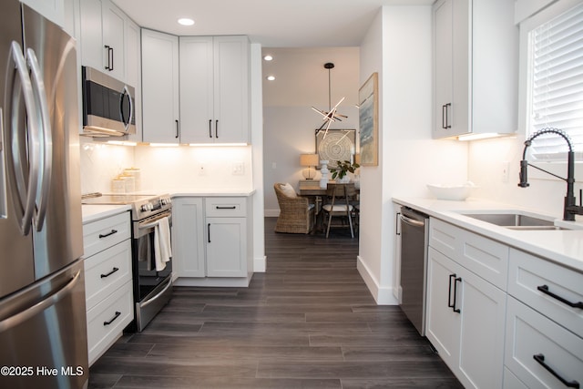 kitchen featuring sink, appliances with stainless steel finishes, backsplash, white cabinets, and decorative light fixtures