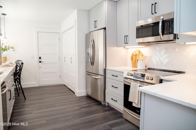 kitchen featuring decorative light fixtures, white cabinetry, dark hardwood / wood-style flooring, decorative backsplash, and stainless steel appliances