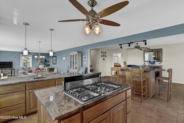 kitchen with a kitchen island, a breakfast bar, open floor plan, stone counters, and stainless steel gas cooktop