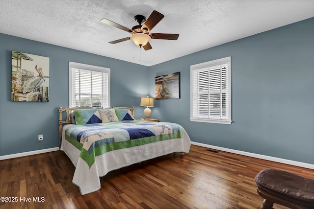 bedroom with a textured ceiling, dark wood-style flooring, visible vents, and baseboards