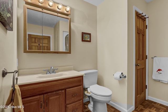 half bathroom with baseboards, vanity, and toilet