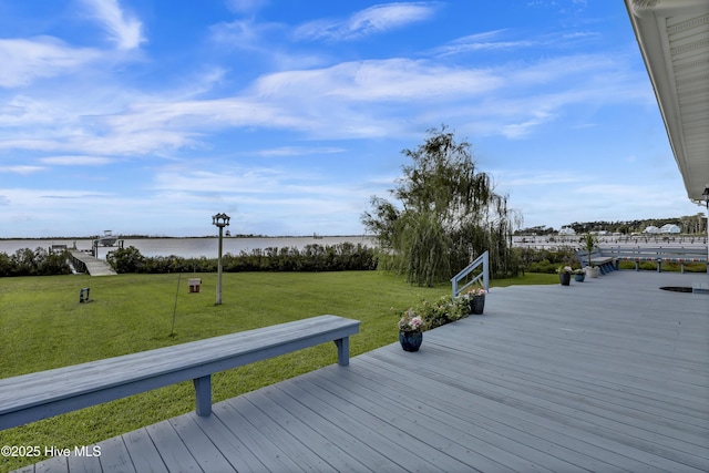 wooden terrace featuring a water view and a lawn