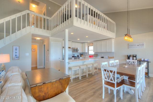 dining space featuring a towering ceiling and light wood-type flooring