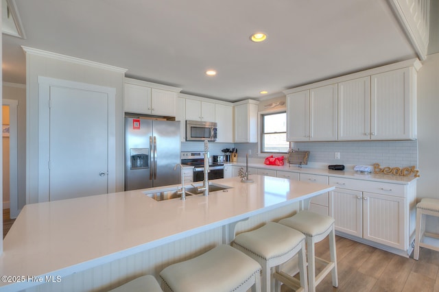 kitchen featuring white cabinetry, a kitchen breakfast bar, an island with sink, and appliances with stainless steel finishes