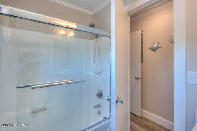 bathroom featuring ornamental molding, hardwood / wood-style floors, and bath / shower combo with glass door