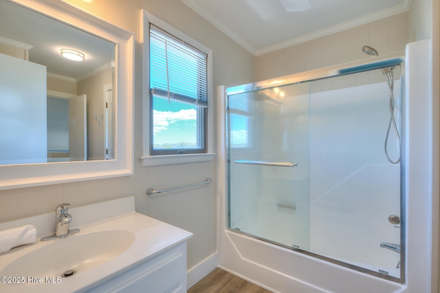 bathroom featuring bath / shower combo with glass door, tile walls, hardwood / wood-style flooring, vanity, and crown molding