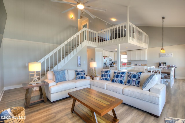 living room with sink, a towering ceiling, ceiling fan, and light wood-type flooring